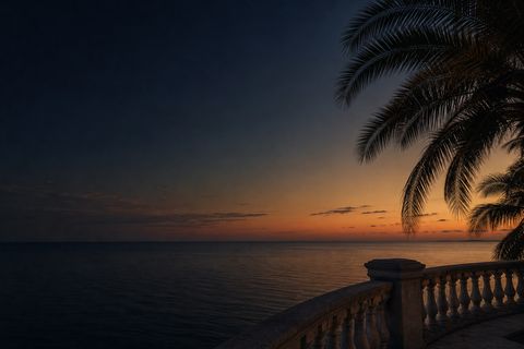 Dusk over calm gulf water with silhouetted palms and a classical stone balustrade
