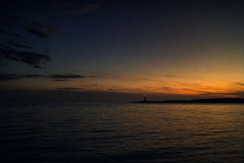 A distant lighthouse beacon across calm water at dusk